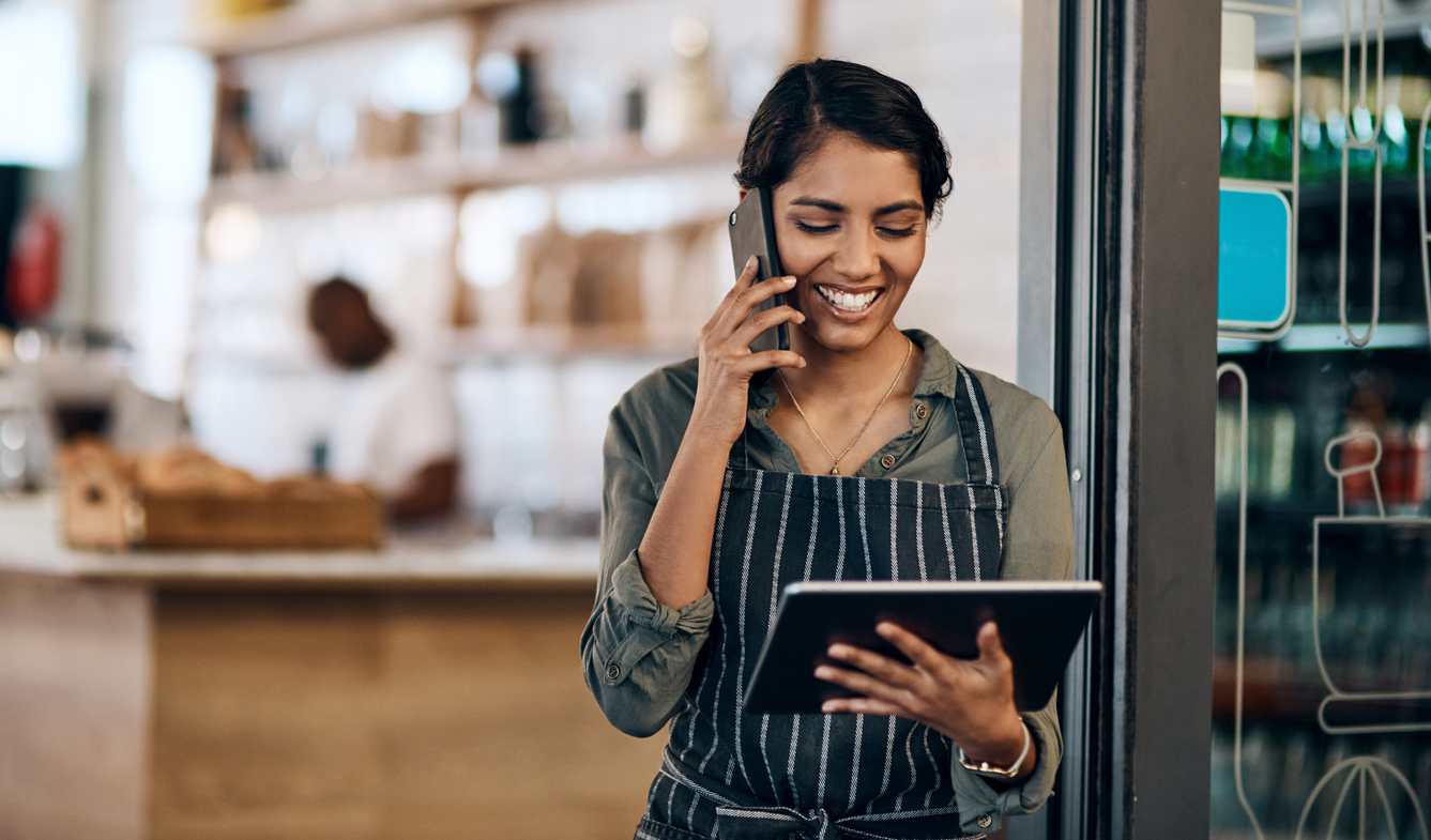 Shot of a young woman using a digital tablet and smartphone while working in cafe