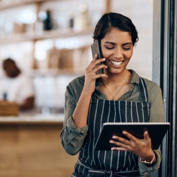 Shot of a young woman using a digital tablet and smartphone while working in cafe